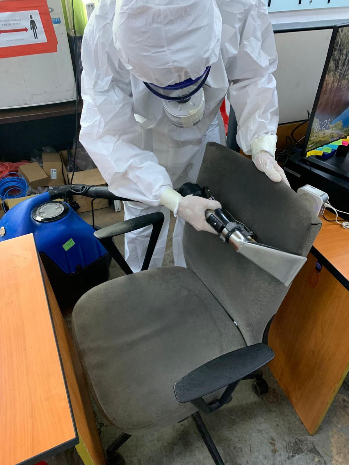 Close-up of technician spraying disinfectant on high-touch office surfaces before antimicrobial coating