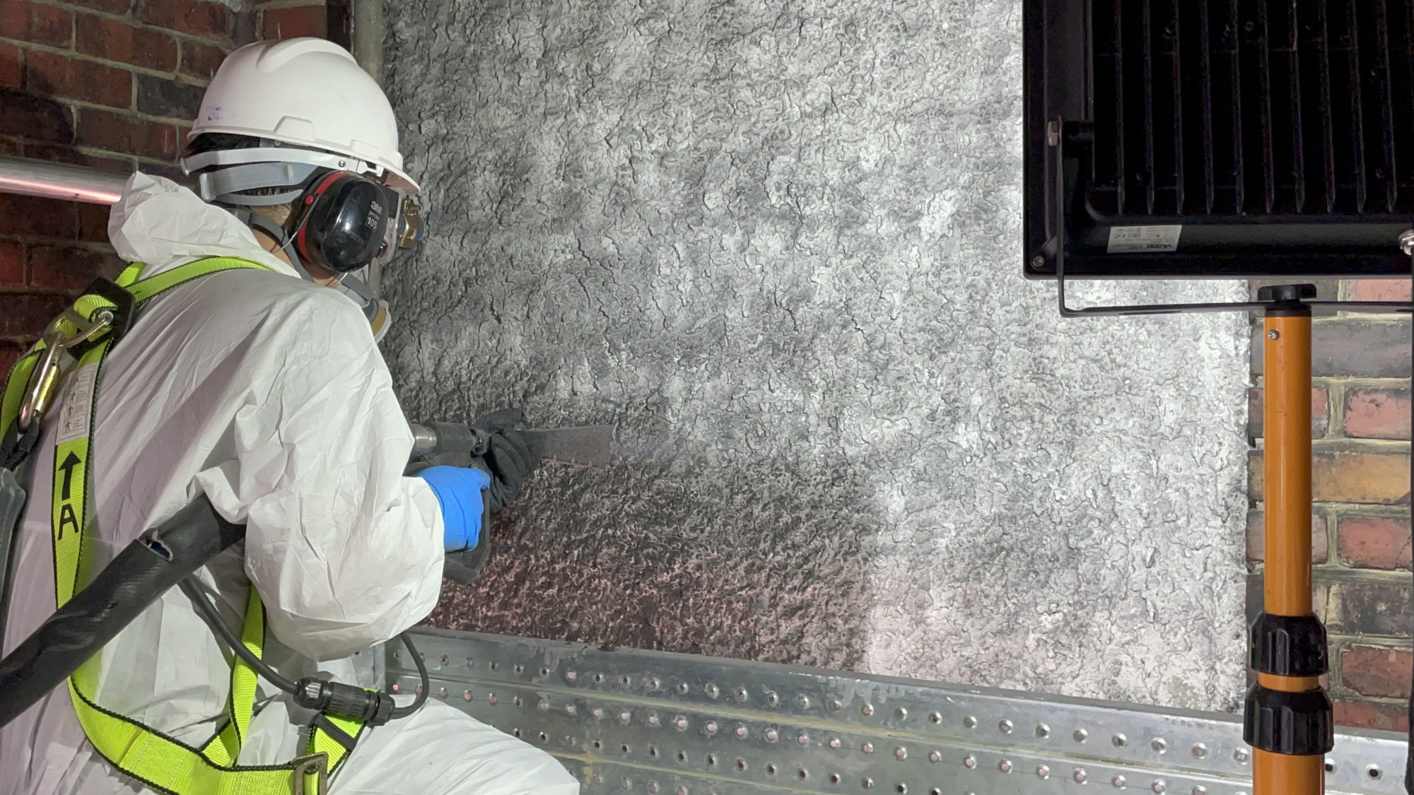 Technician using moisture meter to inspect a wall for hidden mold after flooding